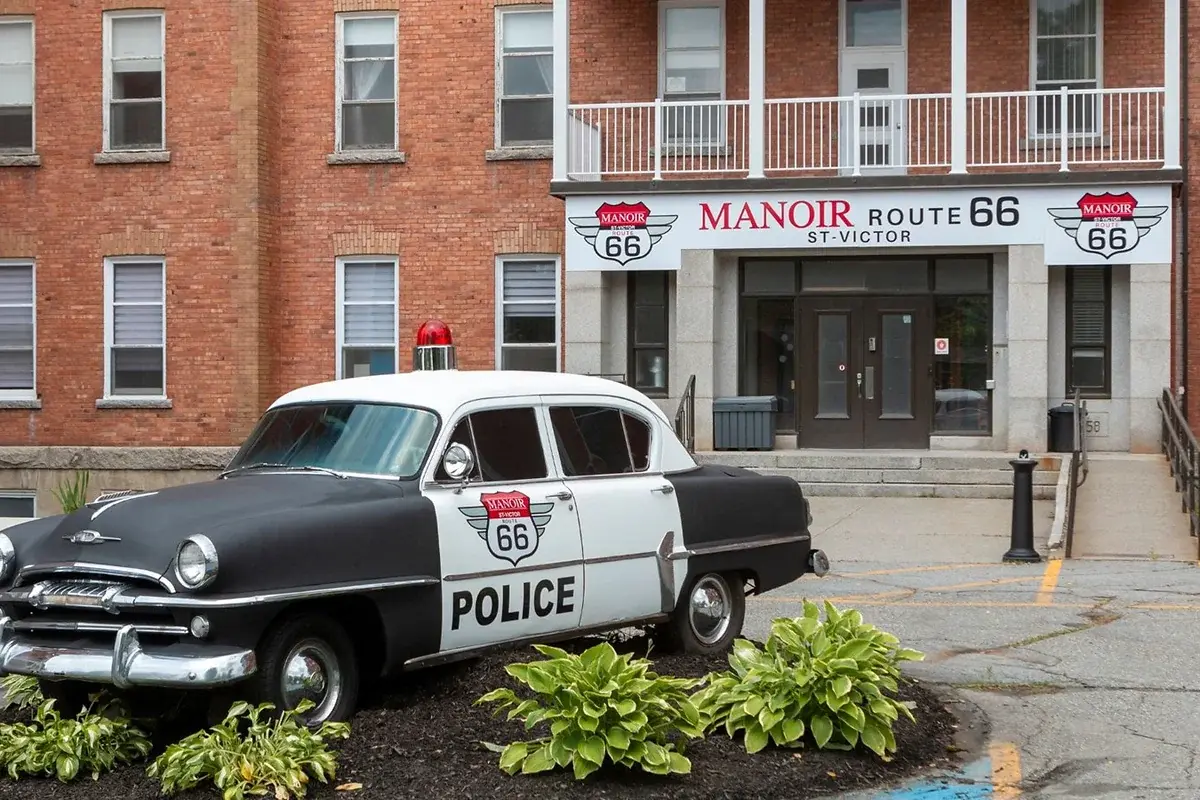 Manoir Historique Route 66 à Saint-Victor avec une voiture de police ancienne